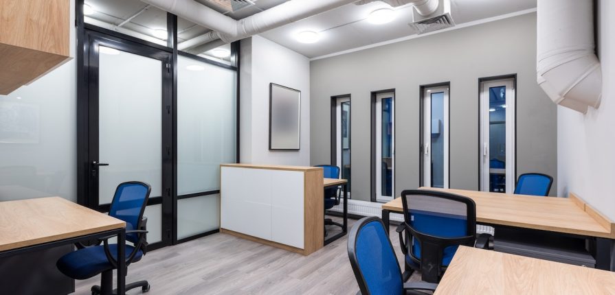 Mobiliario de oficina en madera clara con escritorios de trabajo y módulo central de almacenamiento