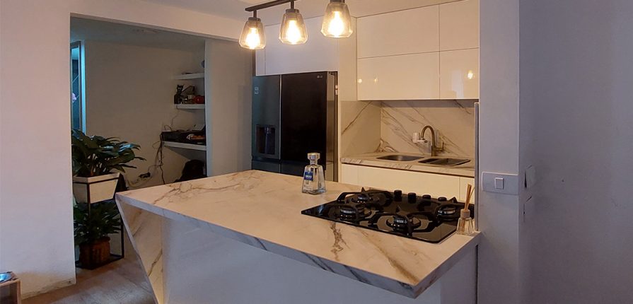 Mobiliario de cocina integral con isla central y superficie tipo mármol